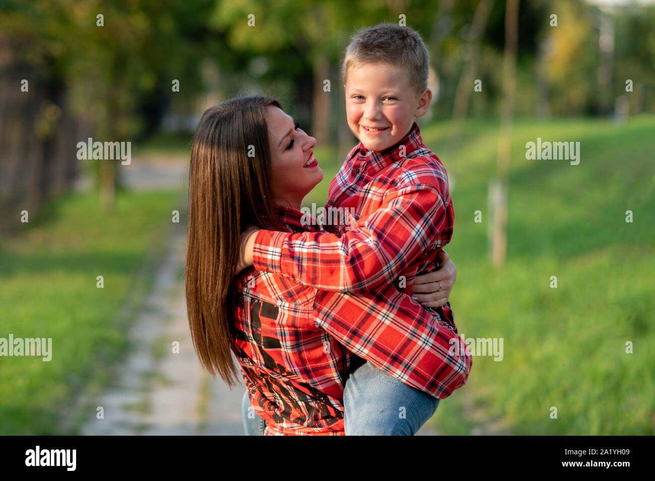 Mom trattiene il suo figlio nelle sue braccia, entrambi sorridente. Foto Stock