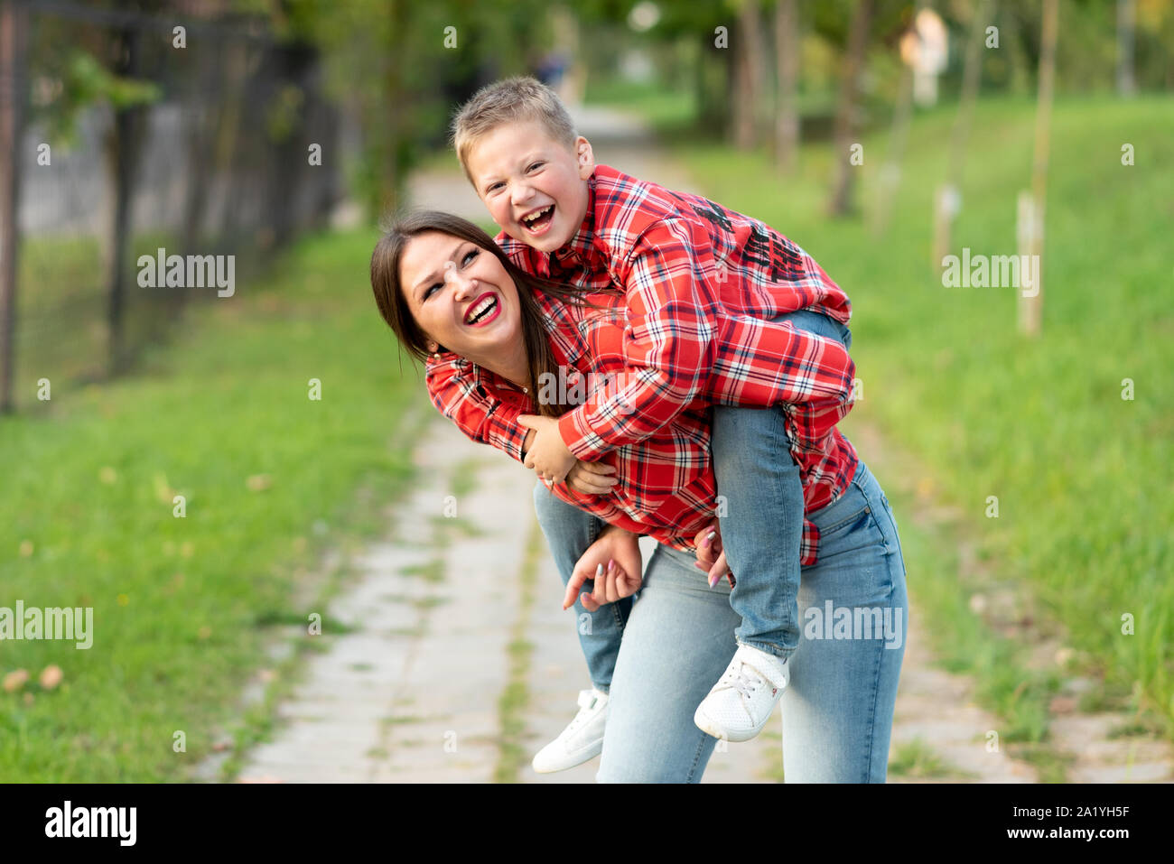 Mom, ridere, detiene sul suo retro un ridere figlio. Foto Stock