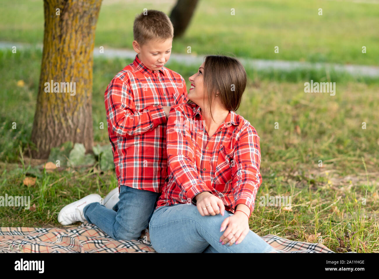 Mom, girando intorno e guarda il suo figlio e sorrisi, seduto sul copriletto. Foto Stock
