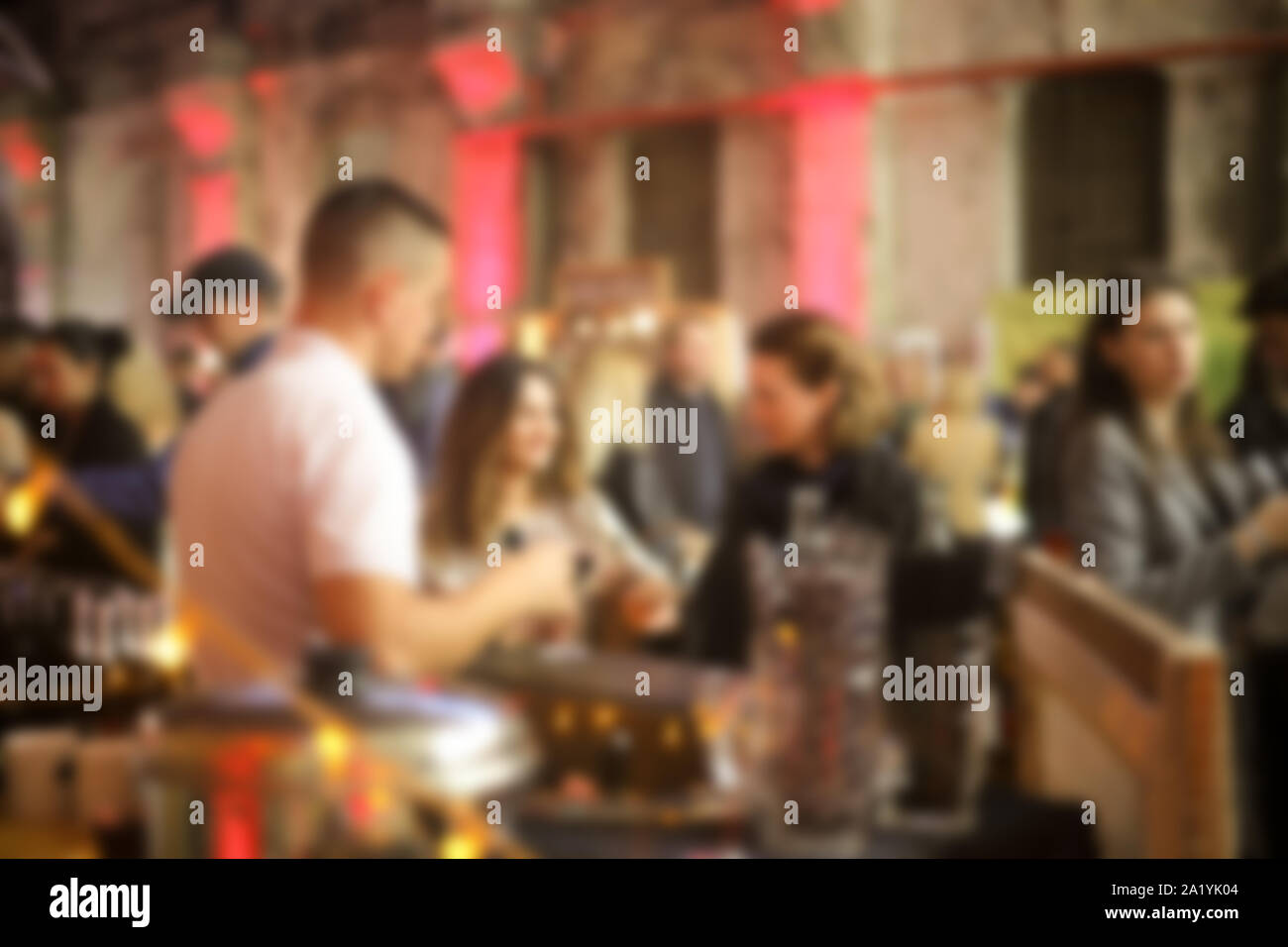 Defocalizzata persone a caso in piedi vicino al bar e il barista. Sfocata evento indoor sfondo. Foto Stock