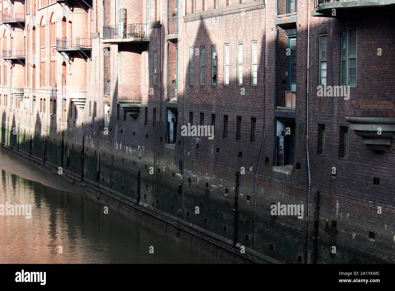 Le ombre degli edifici di fronte a degli edifici adibiti a magazzino di rivestimento del fiume Elba, Amburgo, Germania Foto Stock