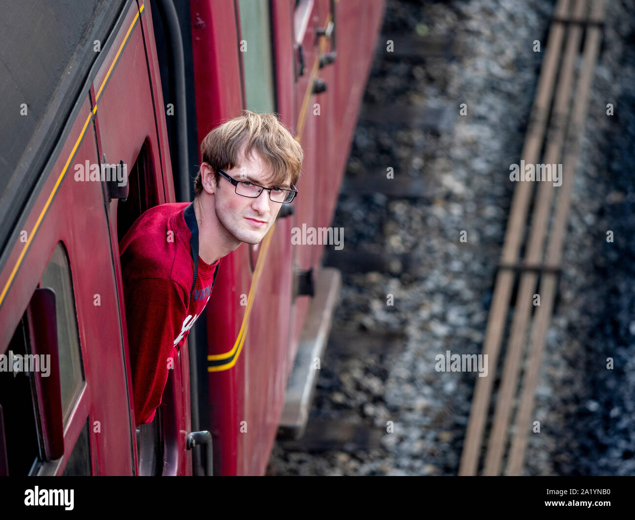 Appassionato di treni che si trova fuori dal finestrino della carrozza sulla North Yorkshire Moors Railway, in attesa di partire dalla stazione di Goathland, Regno Unito Foto Stock