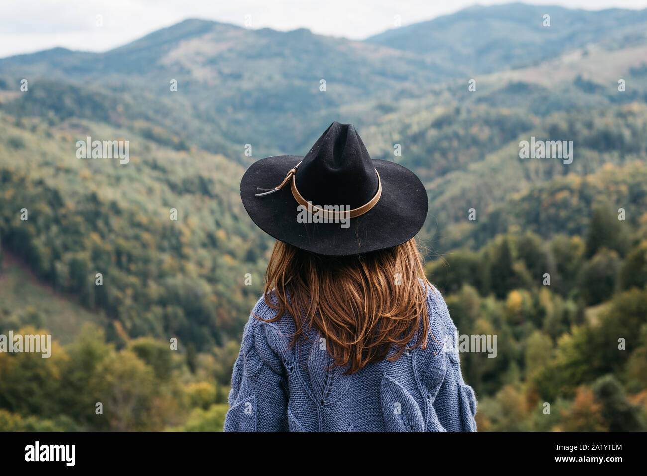 Vista posteriore della bella donna giovane avventuriero o turista si appoggia sul bordo di una scogliera che si affaccia sulla moutains d'autunno. Esplorare il viaggio vero e proprio deserto lifestyl Foto Stock