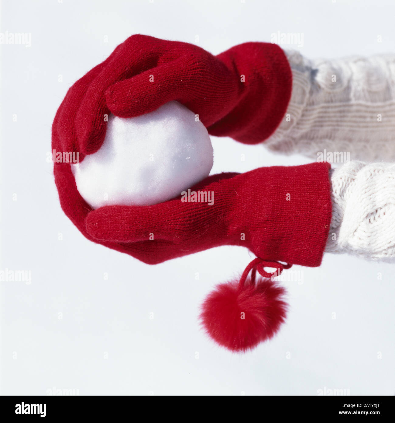 Donna con le mani rosso guanti in maglia tenendo palla di neve. Le persone aventi il divertimento sulla neve all'aperto in inverno. Donna freddo accessori moda. Foto Stock