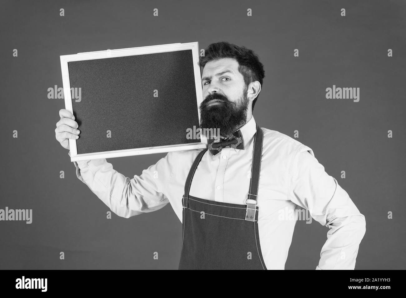 Esclusivo cocktail. Hipster il personale del ristorante. Hipster per informare l'utente. Uomo Barbuto barman o cuoco in attesa della catenaria lavagna vuota. Prezzo di listino del concetto. Hipster barista visualizza blackboard copia spazio. Foto Stock
