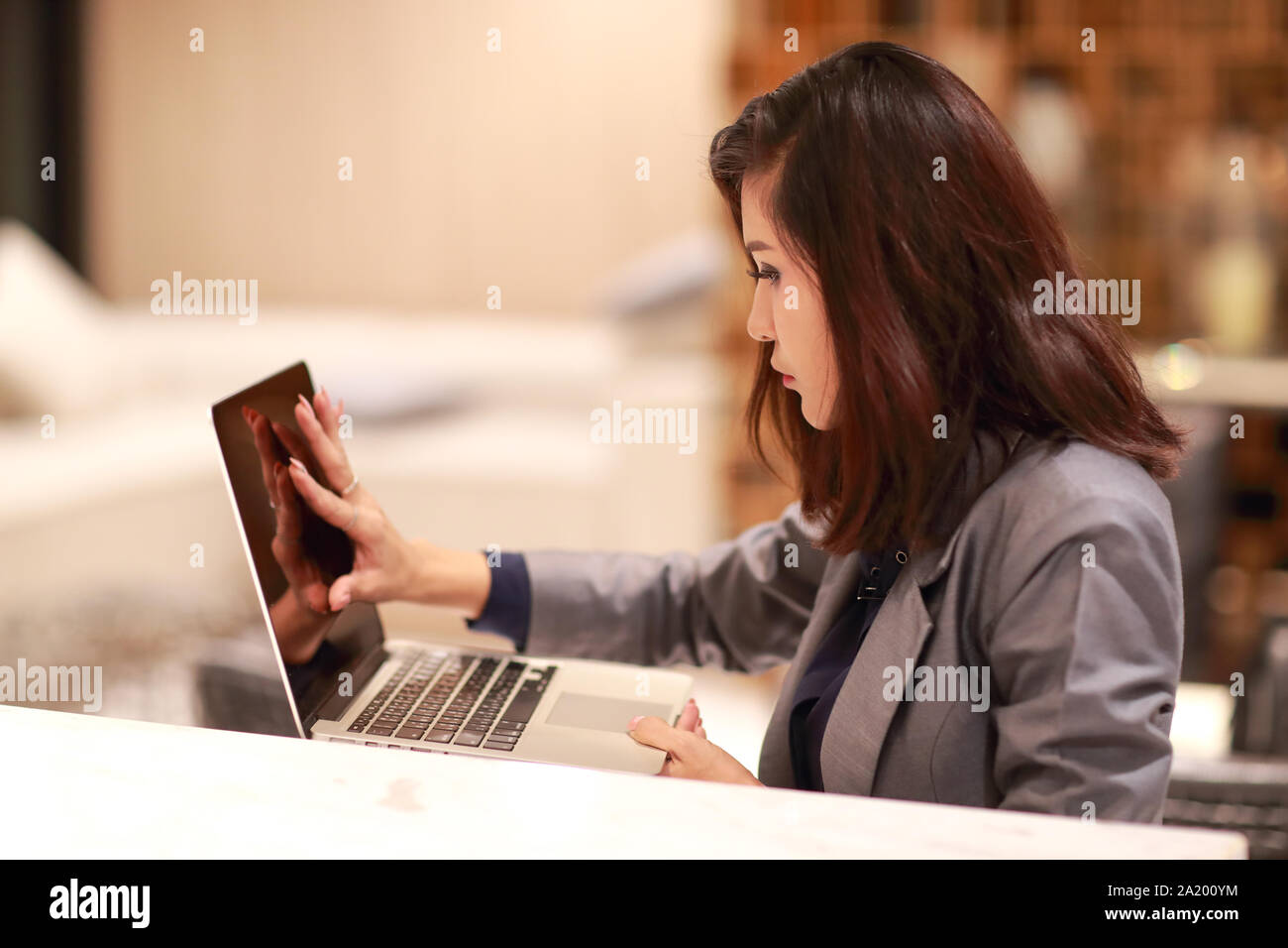 Di lavoro e donna affascinante con gli occhiali usando un computer portatile (lavorare da casa concetto) Foto Stock