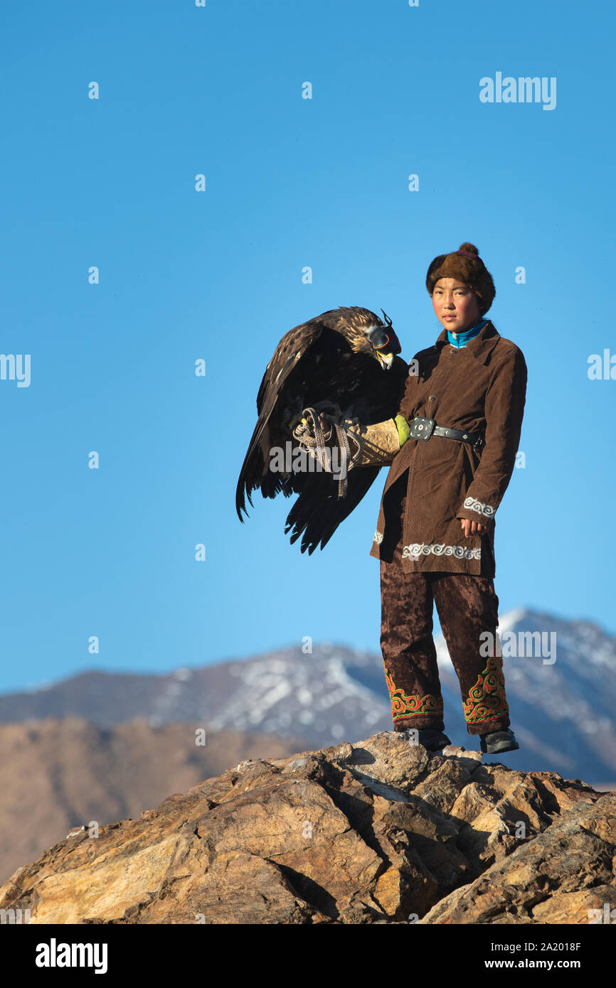 Tradizionale aquila kazaka cacciatrice su una scogliera con il suo golden eagle che è utilizzato per la caccia di Fox e Pelo Coniglio. Ulgii, Mongolia occidentale. Foto Stock
