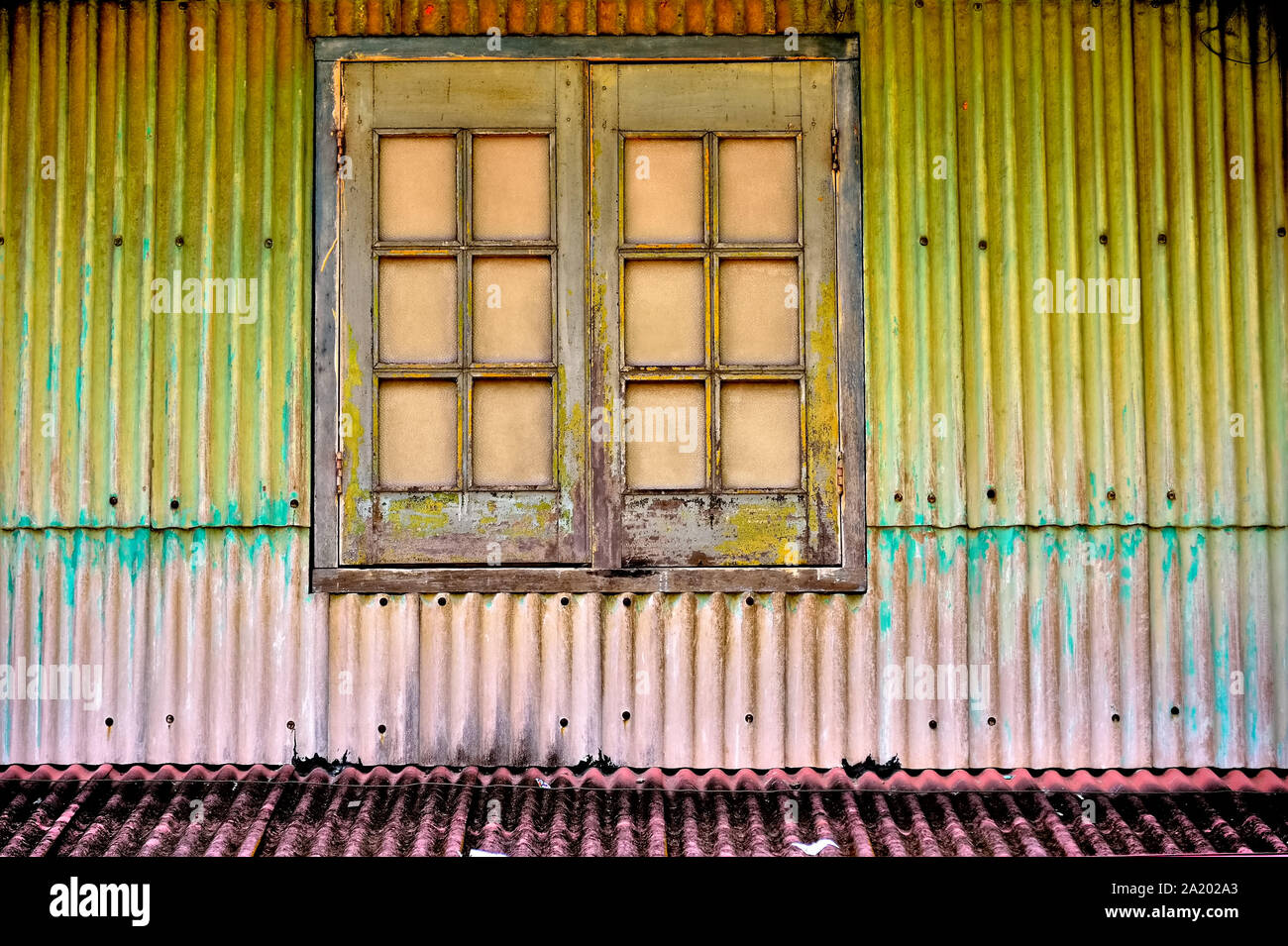 Finestra di antiquariato marrone con persiane di legno su metallo ondulato esterno della casa di Geylang, Singapore Foto Stock