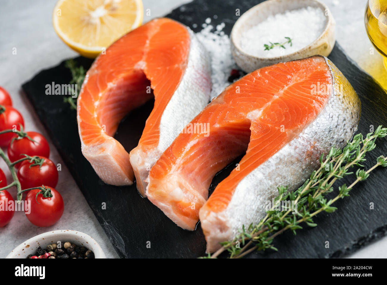 Due filetti di salmone, le spezie e le erbe aromatiche per la cottura sul nero ardesia. Cibo sano concetto. Messa a fuoco selettiva Foto Stock