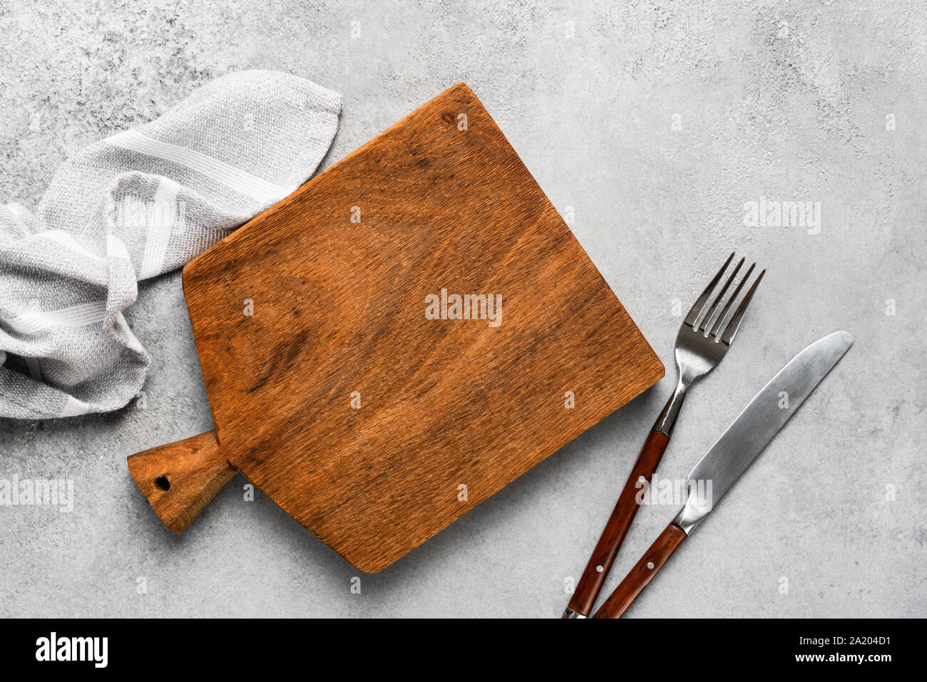 Tagliere di legno, lino tessile e posate. Sfondo di cibo con copia spazio. Tabella vista superiore Foto Stock