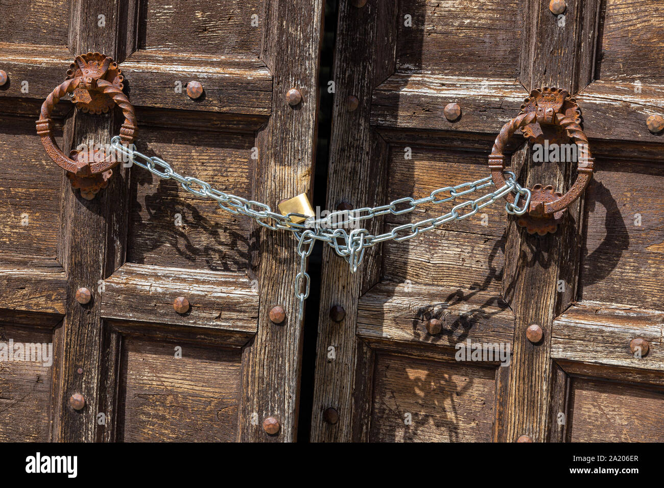 Vecchia porta di legno in Toscana, Italia. Leggermente socchiuse ma bloccato con una catena di moderna Foto Stock
