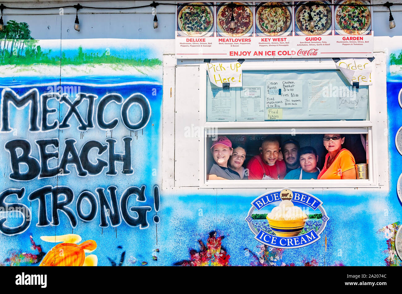 I dipendenti di raccogliere in una finestra accanto a "Messico Beach Strong" murale a Crazy Beach Pizza, Sett. 27, 2019, in Messico Beach, Florida. Foto Stock
