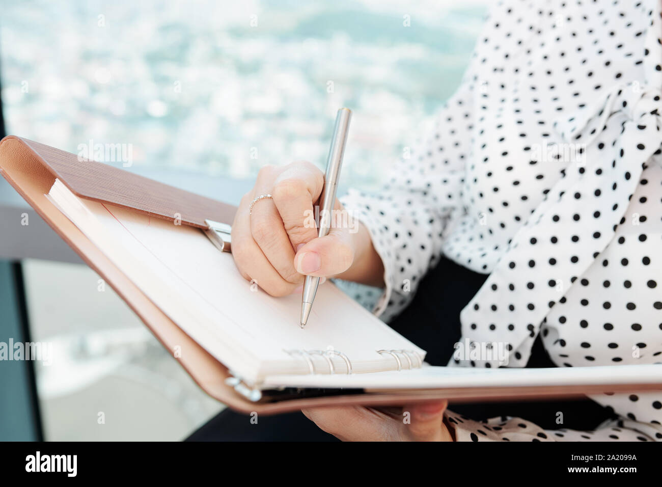 Close-up di immagine imprenditrice seduto alla finestra di ufficio e la scrittura di idee nel planner Foto Stock