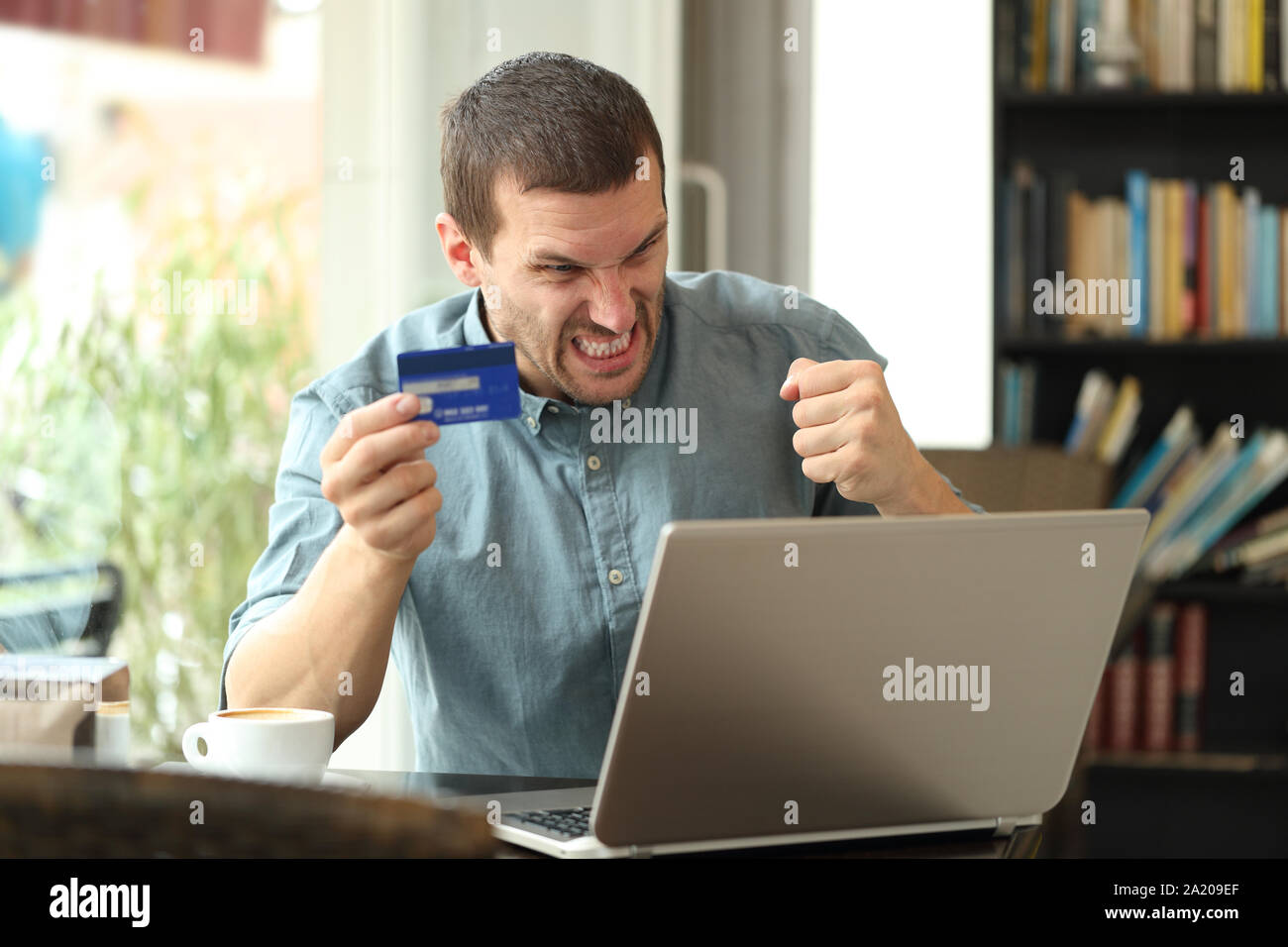 Angry Man avendo problemi per pagare online con carta di credito seduti in un caffè Foto Stock