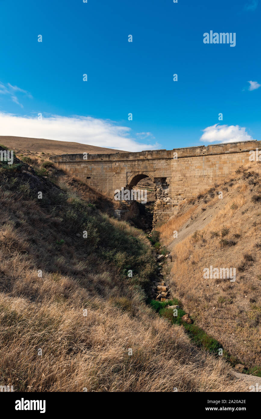 Il vecchio fatiscente ponte in pietra sopra un piccolo fiume di montagna Foto Stock