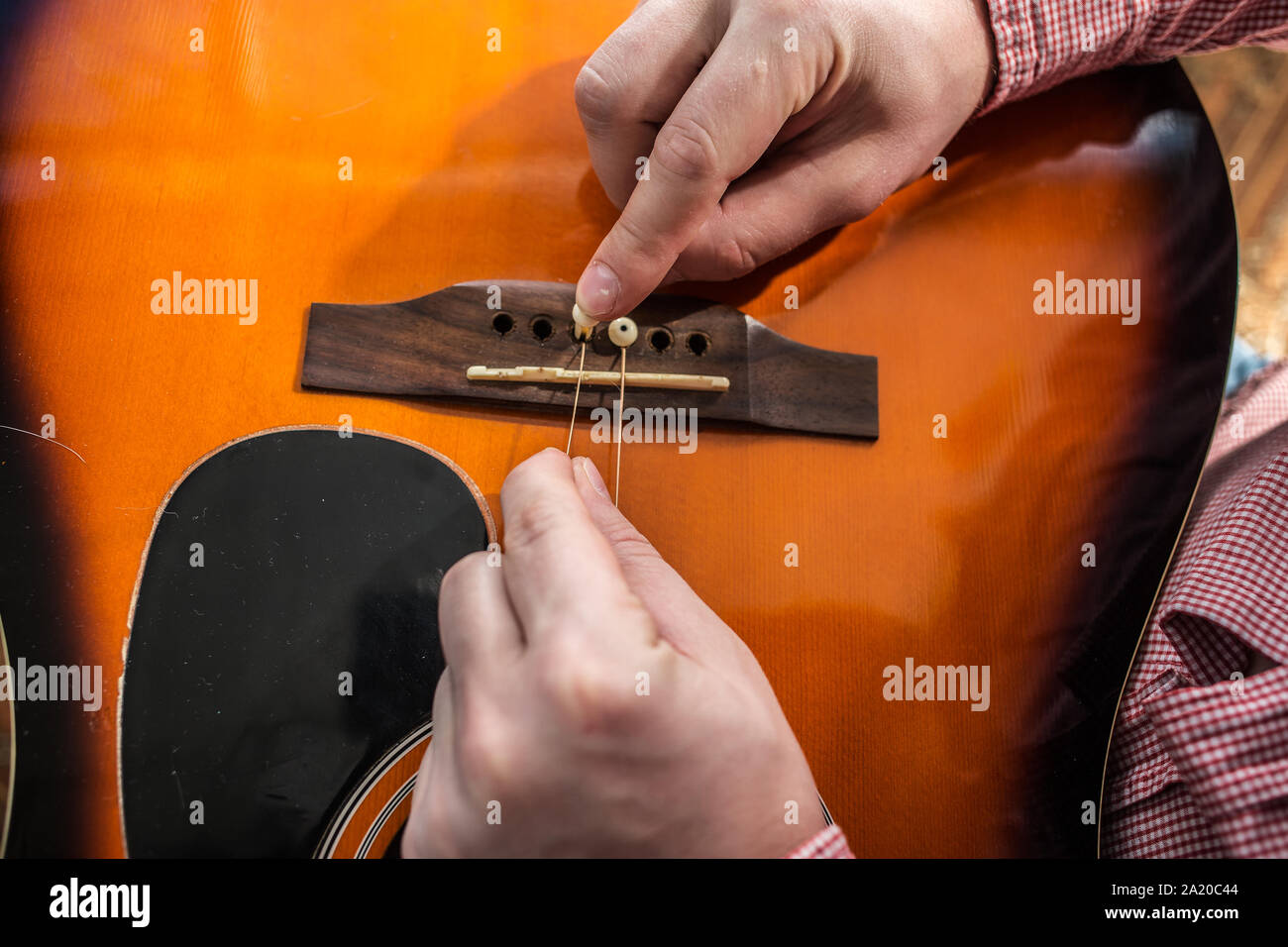 L'uomo passa di mano vecchia strappato le corde di una chitarra sulla chitarra acustica sul nuovo Foto Stock