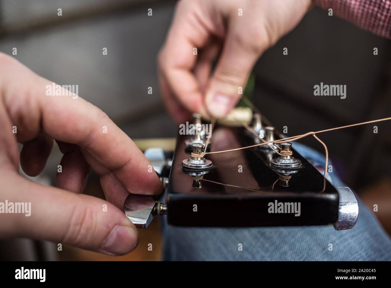 Un uomo in un plaid shirt tira di nuovo le corde di una chitarra chitarra acustica close-up Foto Stock