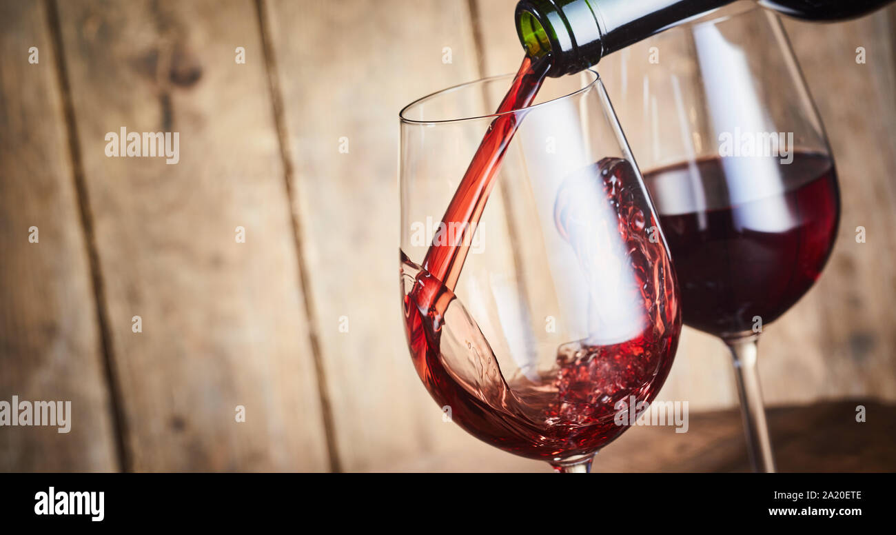 Versando un rosso vino di Bordeaux da Garonne Francia in eleganti wineglasses con congelare il movimento splash in una vista ravvicinata e spazio di copia Foto Stock