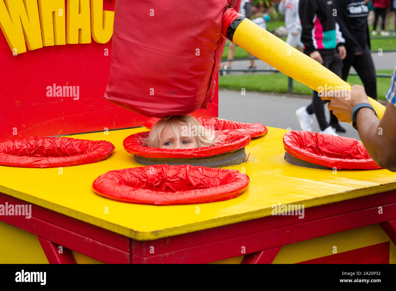 Bambino essendo whacked sulla testa con un gigantesco martello schiuma umani nel pop-up al gioco delle arti dal mare festival, Bournemouth Dorset, Regno Unito, Settembre 2019 Foto Stock