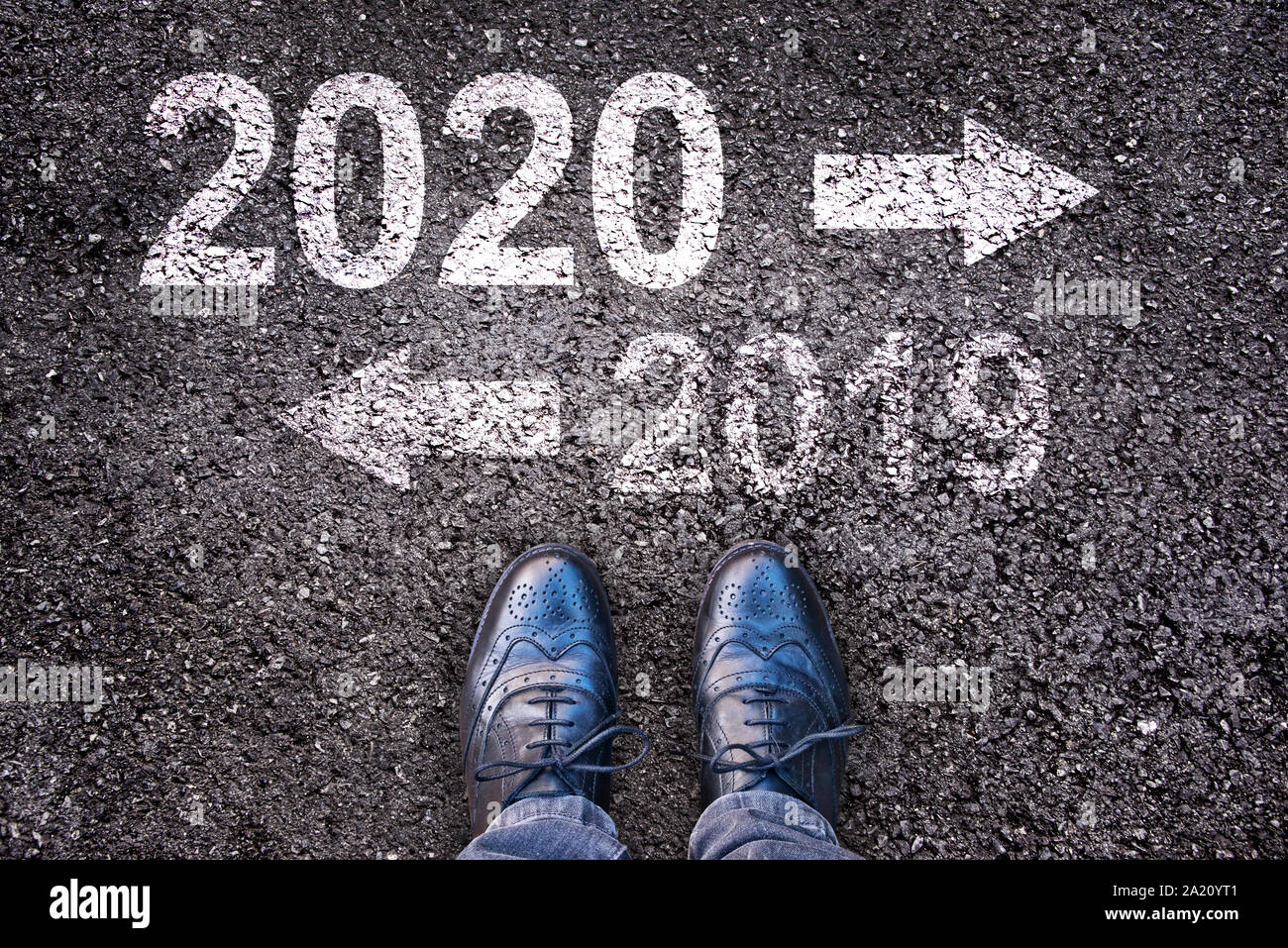 2020 e 2019 con frecce di direzione scritto su una strada asfaltata sfondo con gambe Foto Stock