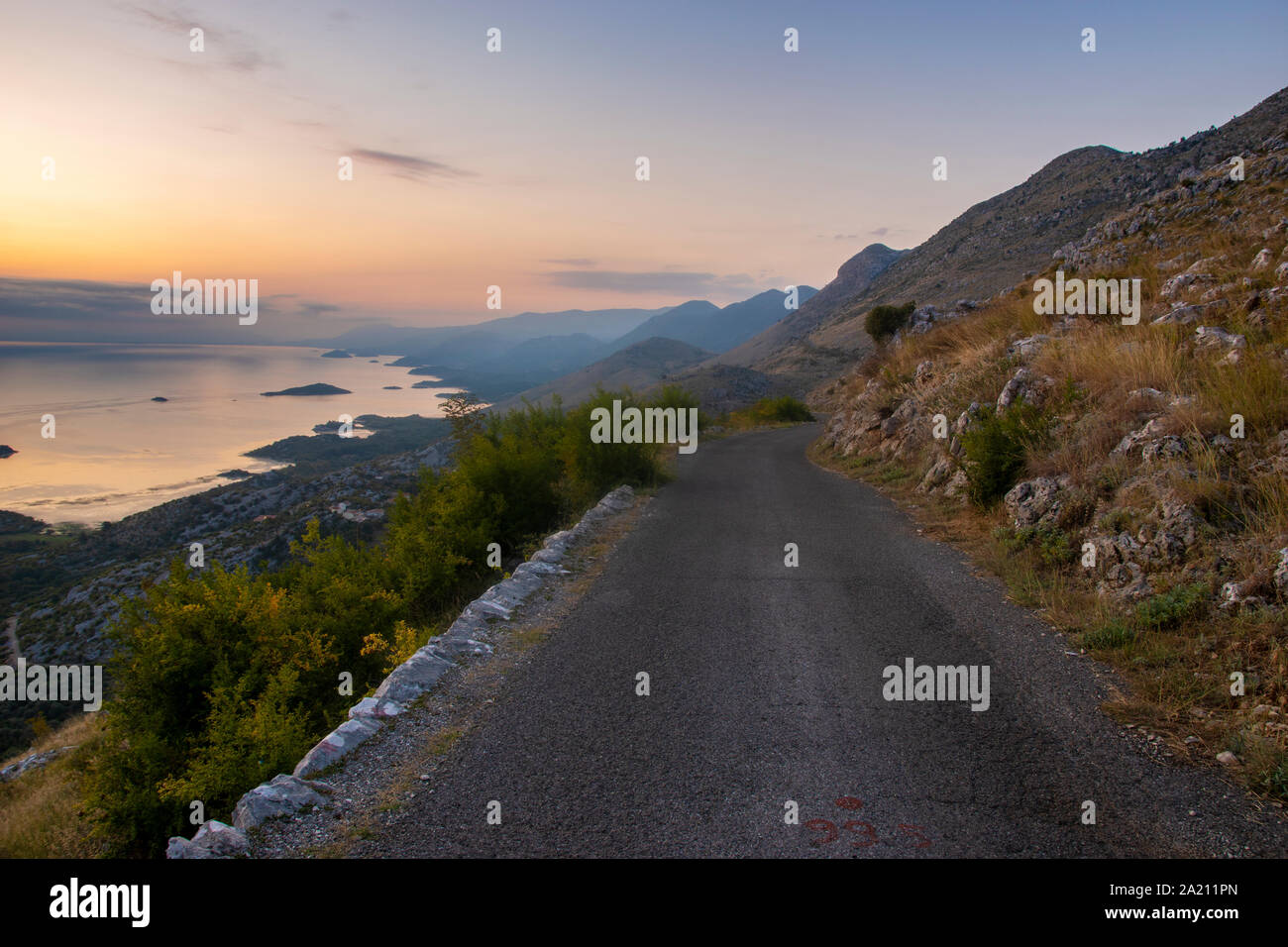 Una stretta e tortuosa strada che corre sul bordo di una scogliera sopra il Lago di Scutari in Montenegro Foto Stock