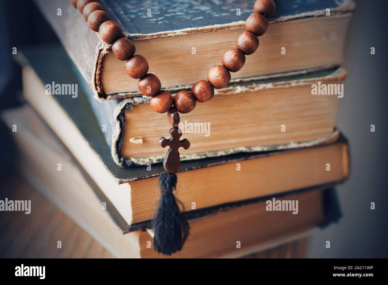 Il sacro rosario, di mogano, giace su di una pila di vecchi libri martoriata in cui i precetti religiosi sono scritti. Foto Stock