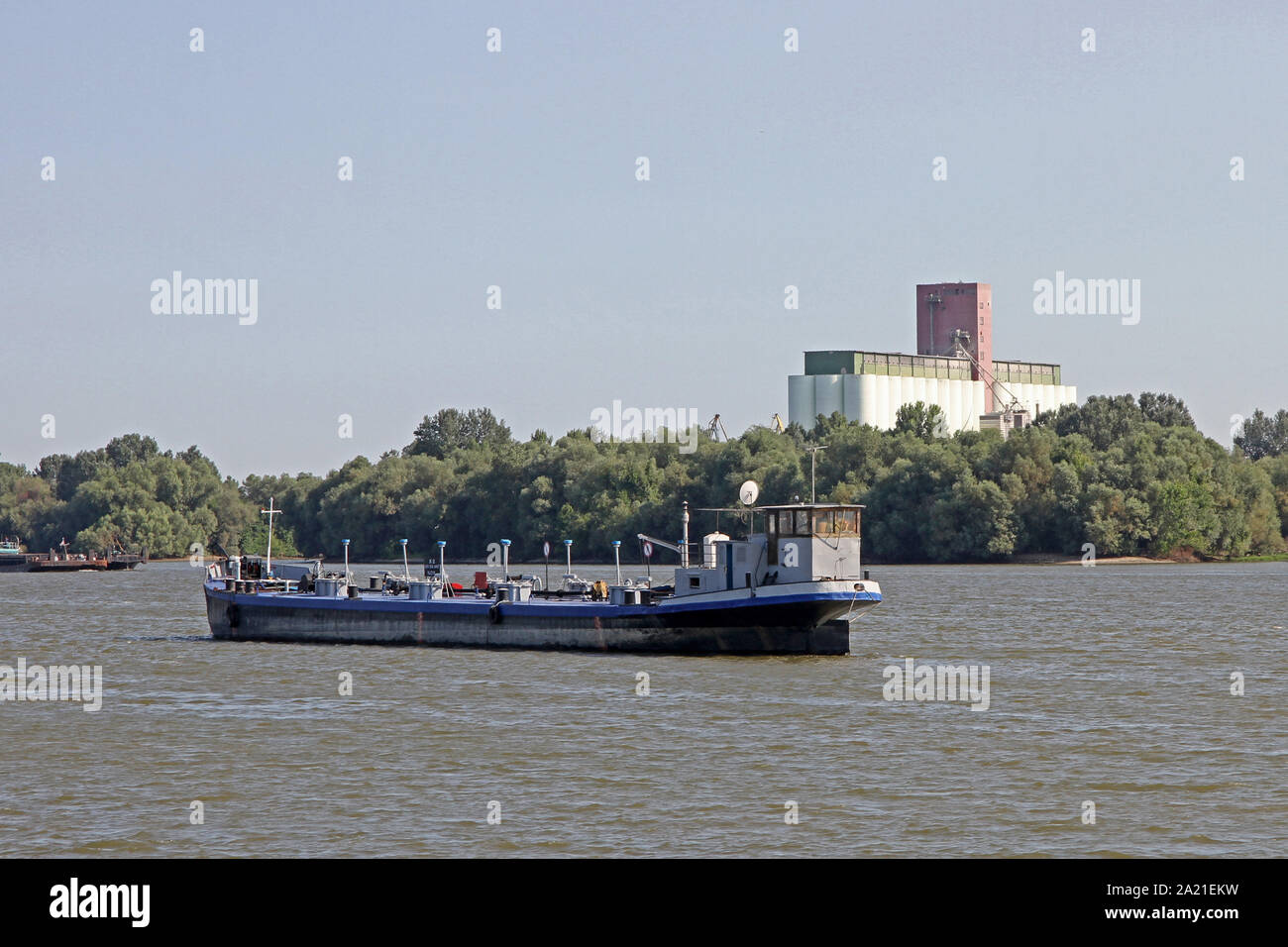 Vista della petroliera sul fiume Danubio vicino a Belgrado con alberi sulla riva con silos per il grano dietro di esso, Fiume Danubio, Serbia. Foto Stock