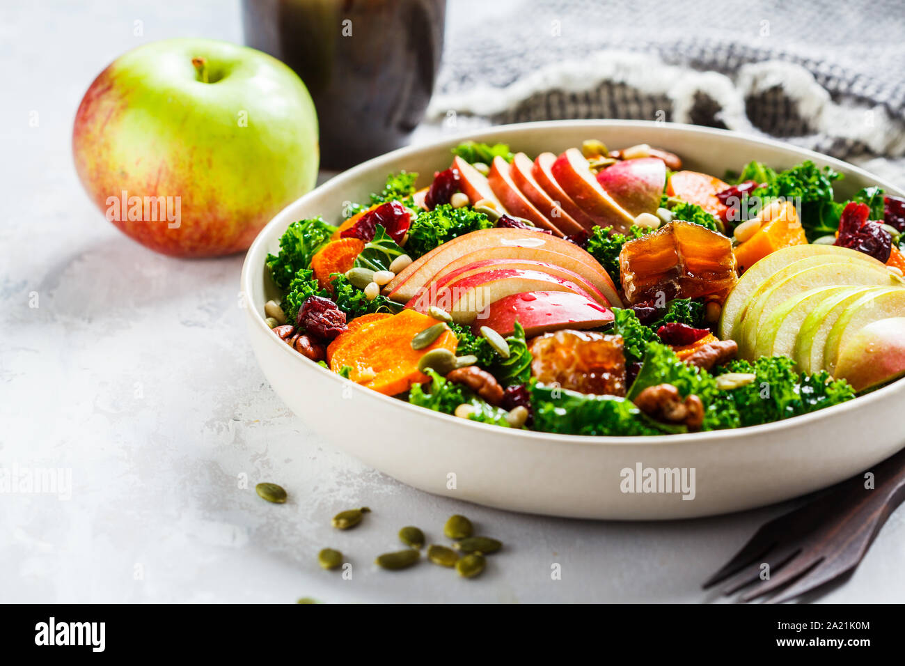 Insalata invernale con Apple, zucca, mirtilli rossi, il miele e i semi in una piastra bianca. Sano cibo vegan concetto. Foto Stock