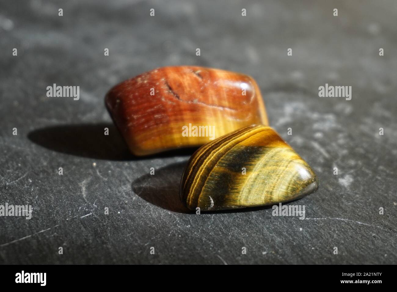 L'occhio della tigre ha rotolato ciottoli su sfondo grigio ardesia, illuminato dal sole Foto Stock