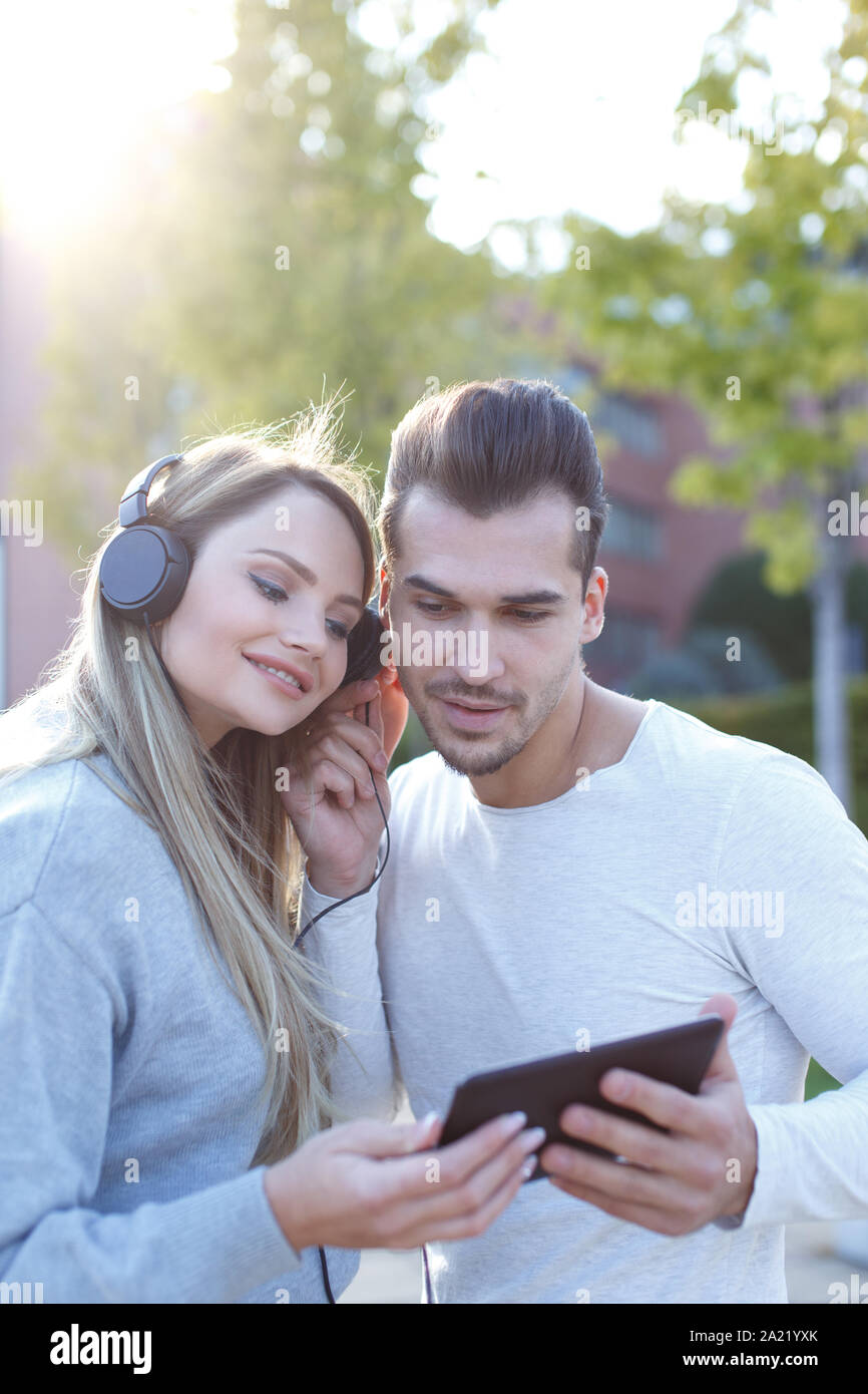 Coppia giovane ascoltando musica dal tablet e cuffie, tecnologia wireless, gli auricolari di condivisione Foto Stock