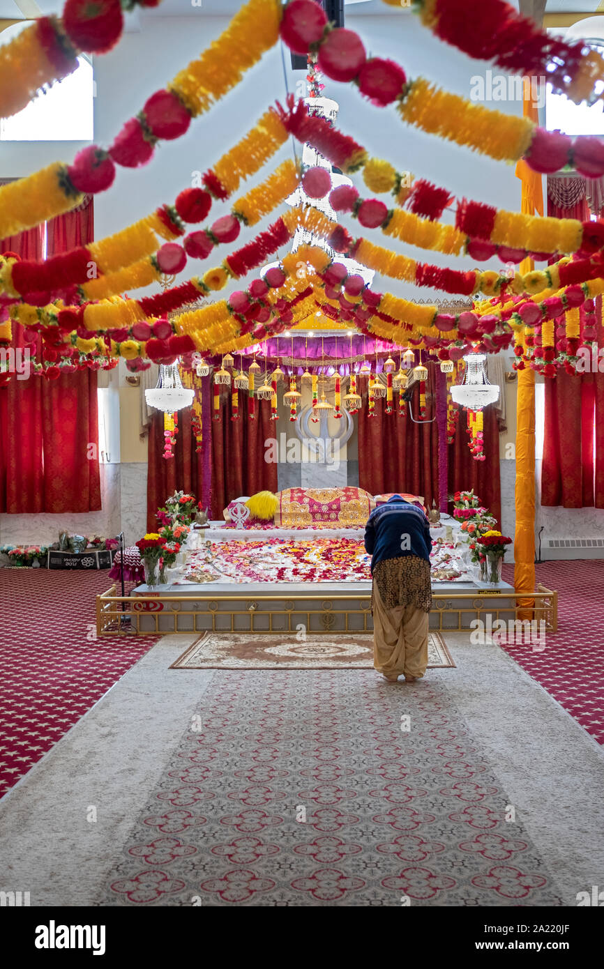 Una donna Sikh all altare della religione Sikh Società culturale di tempio in Richmond Hill, Queens, a New York appositamente decorate per il compleanno del Guru Nanak. Foto Stock