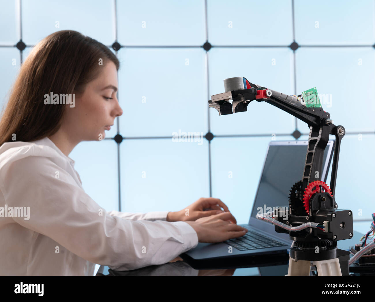 Una giovane donna scrive un algoritmo per il braccio del robot. La scienza laboratorio di ricerca per il braccio robotico modello. Laboratorio di Computer Foto Stock