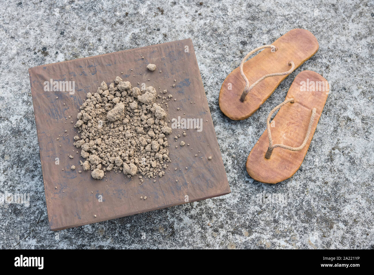 Usurati flipflops hippy e quadrato con messa a terra su una superficie in calcestruzzo. Metafora terra piatta teoria, flat earthers, teorie cospirative, piano terra la prova. Foto Stock