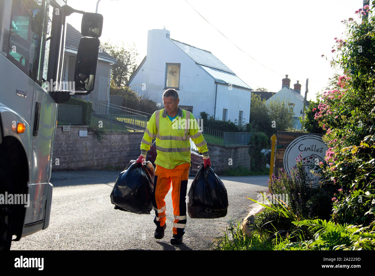 Consiglio lavoratore nero con sacchetti di plastica e camion di raccolta rifiuti domestici nel villaggio di Marloes Pembrokeshire in West Wales UK KATHY DEWITT Foto Stock