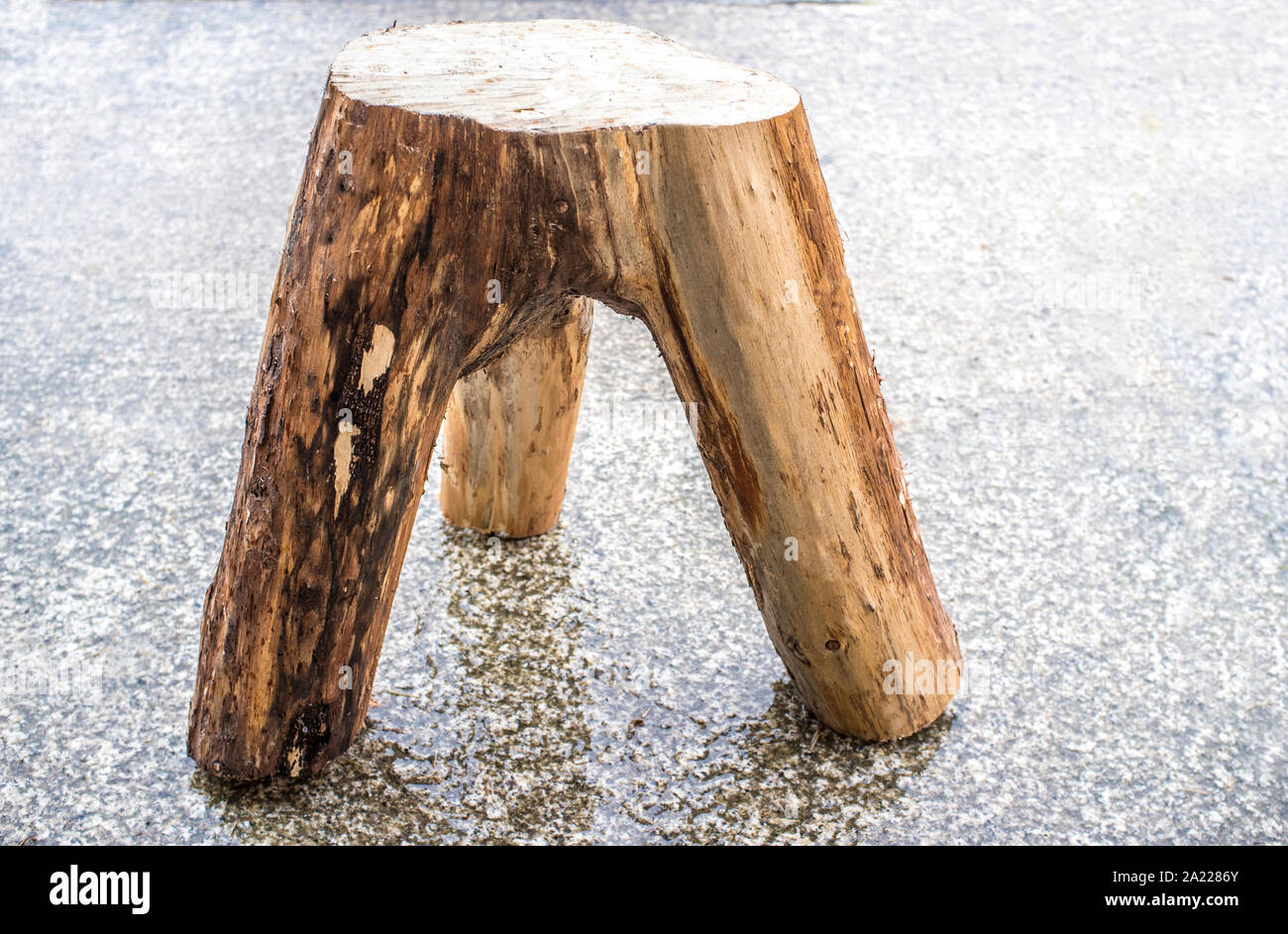 Tre gambe moncone sgabello realizzato con il tronco e i rami principali. Rustico design home Foto Stock