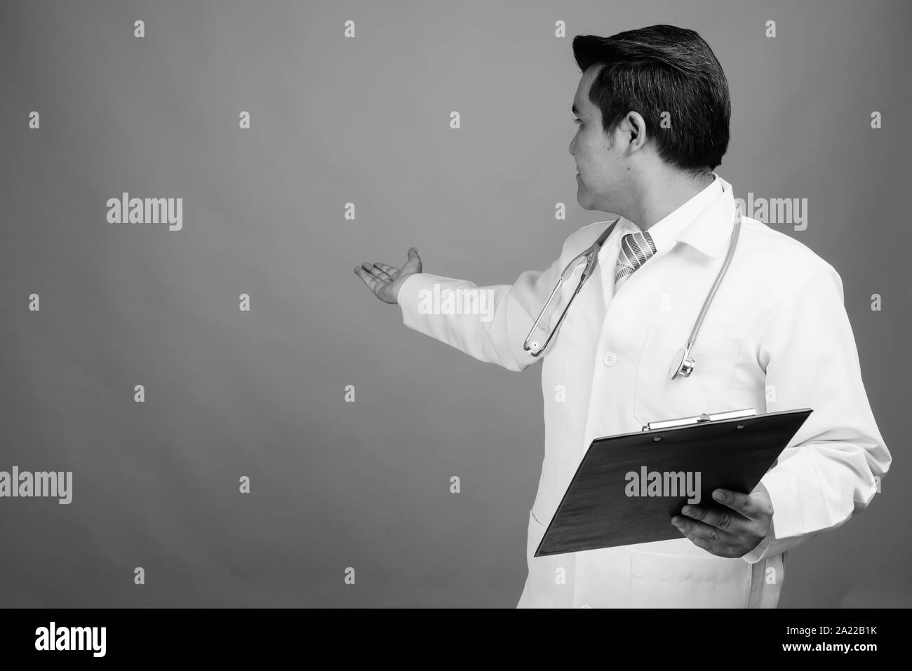 Giovani multi-etnico medico uomo contro uno sfondo grigio Foto Stock