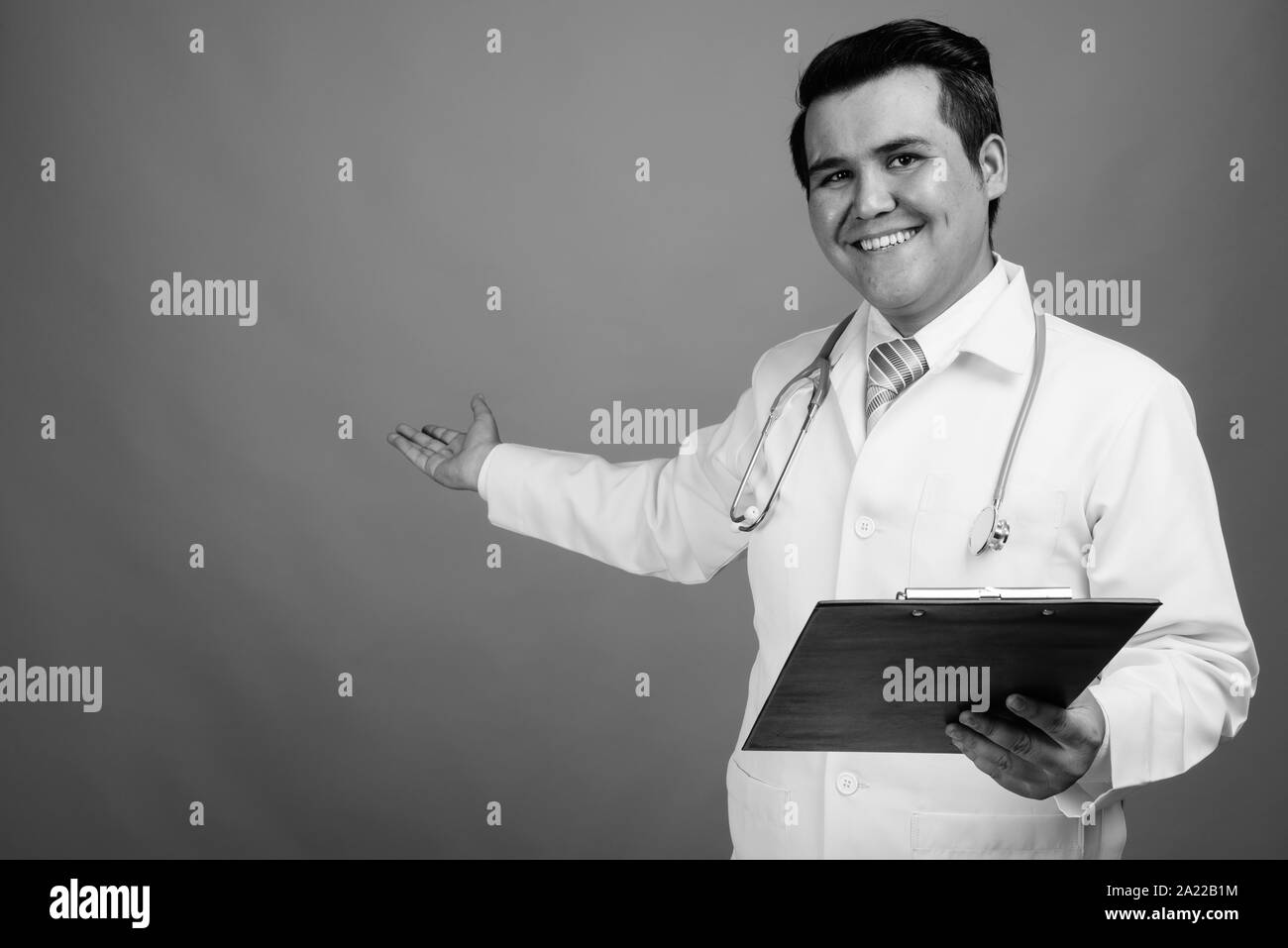 Giovani multi-etnico medico uomo contro uno sfondo grigio Foto Stock