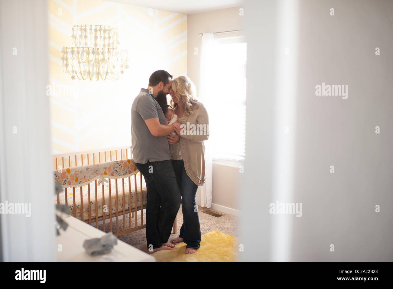 Nuova famiglia felicemente cuddling insieme a casa nel neonato la Camera del neonato Foto Stock