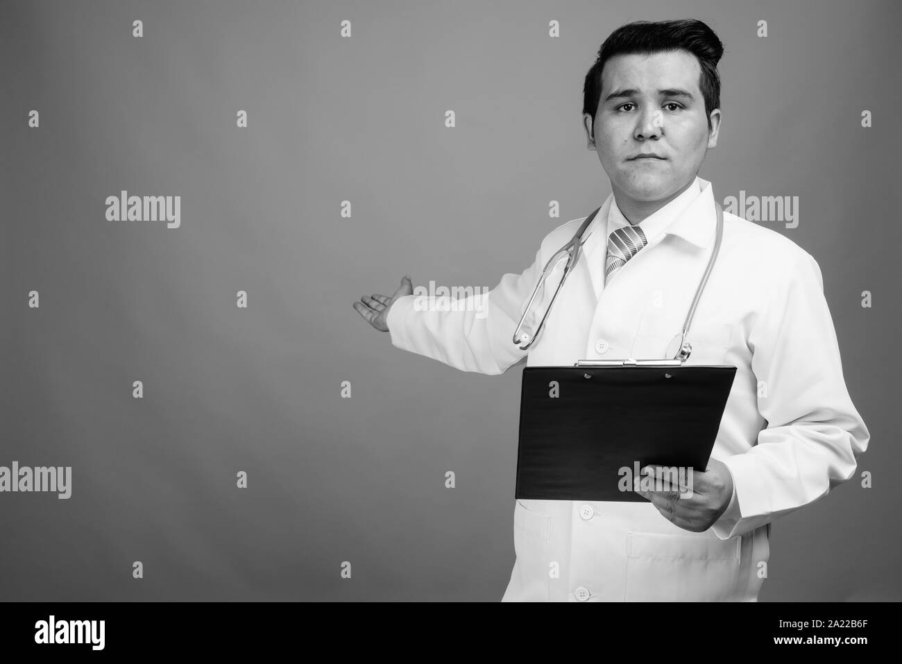 Giovani multi-etnico medico uomo contro uno sfondo grigio Foto Stock