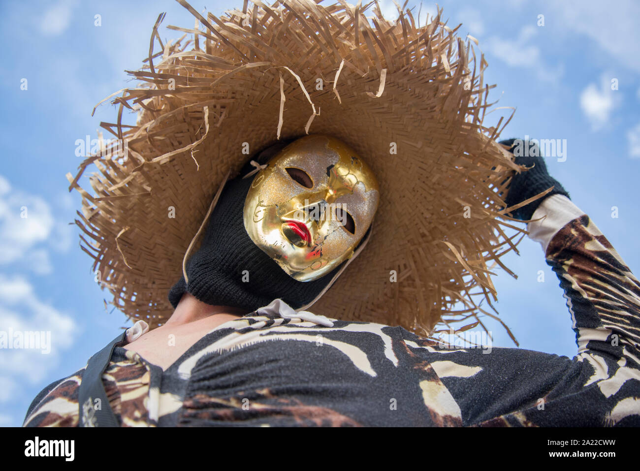 Reveler indossando il costume della maschera d'oro e il cappello di paglia Foto Stock