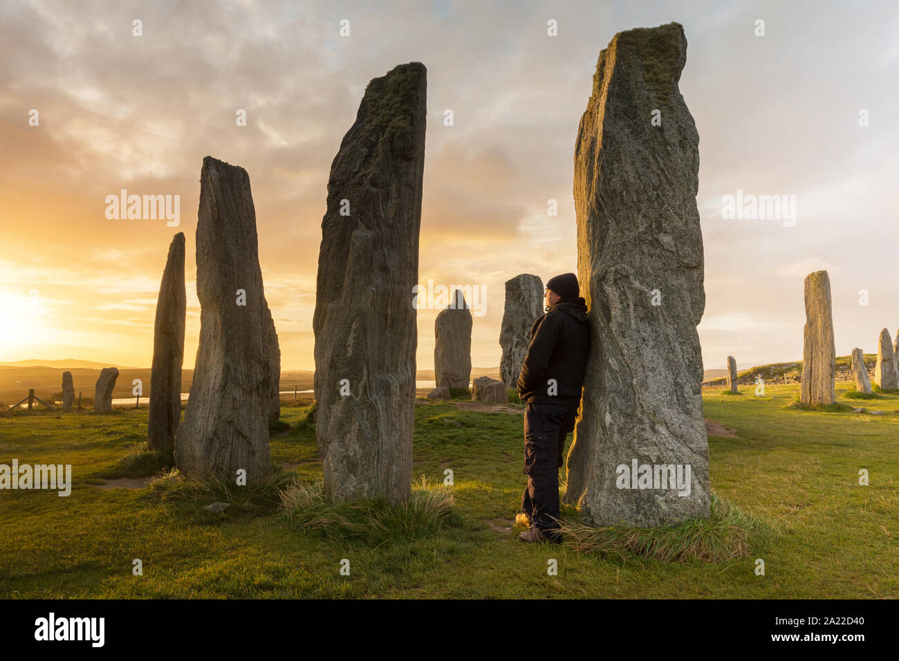 Un uomo si erge tra il Callanish stone circle, un sito neolitico di importanza storica dell'isola di Lewis in Scozia. Foto Stock