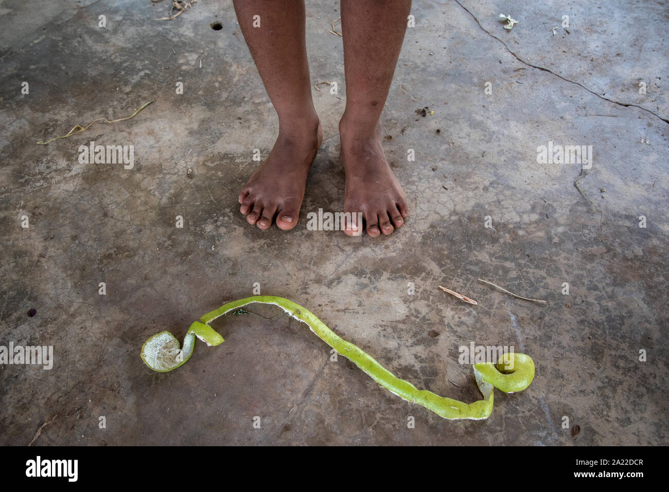 Afro-brasiliano ragazzo in piedi e buccia di arancia sul pavimento rustico Foto Stock