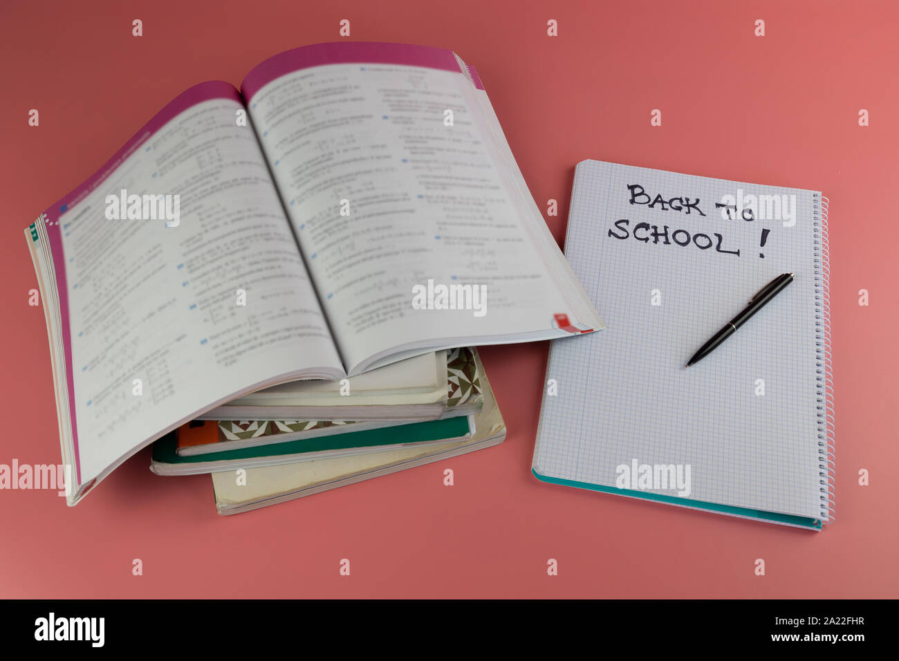 Si torna a scuola concetto, libri e aprire il notebook con le parole si torna a scuola scritto su di esso, su un sfondo rosa Foto Stock