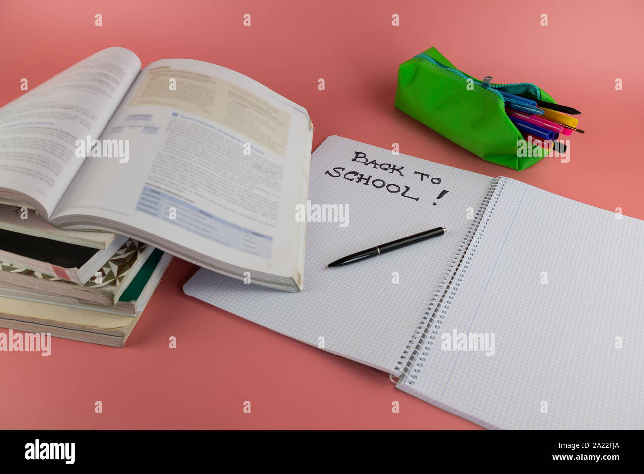 Si torna a scuola concetto, libri e aprire il notebook con le parole si torna a scuola scritto su di esso, su un sfondo rosa Foto Stock