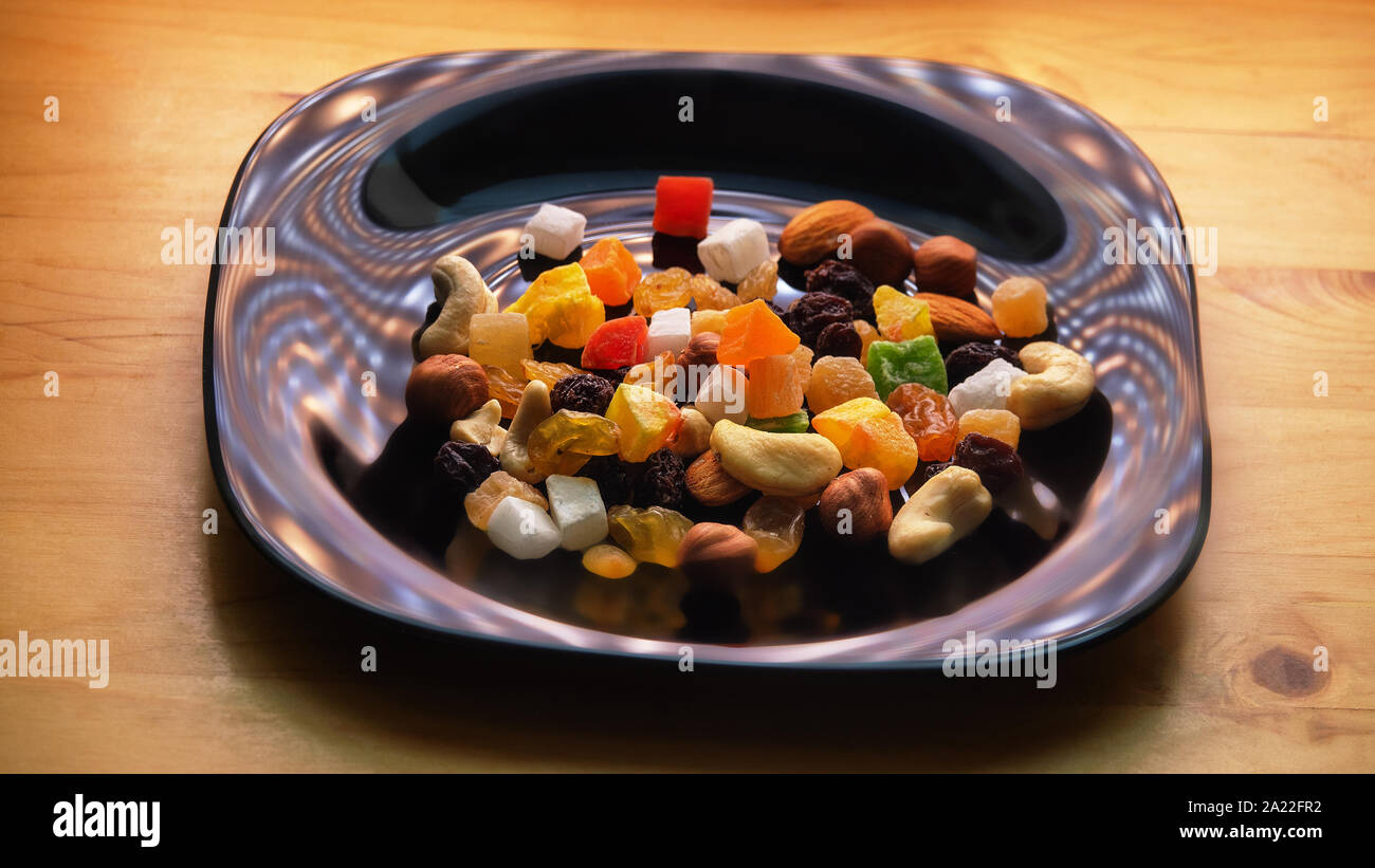 Tutti frutti. Mix di frutta secca (uva passa, cedro, mango) e dadi (mandorle, nocciole) su un nero laccato piatto Foto Stock