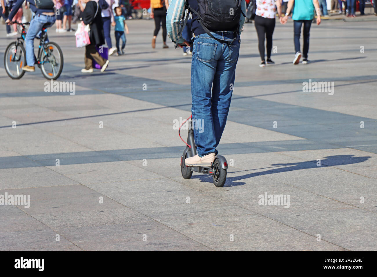 Uomo a cavallo di un kick scooter presso la piazza della città Foto Stock
