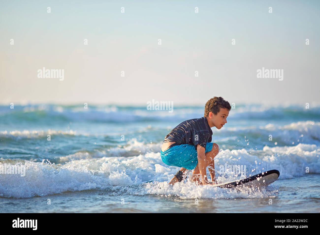 Esperto di adolescente a cavallo con la tavola da surf e il bilanciamento di un lungo mare ondeggiante Foto Stock