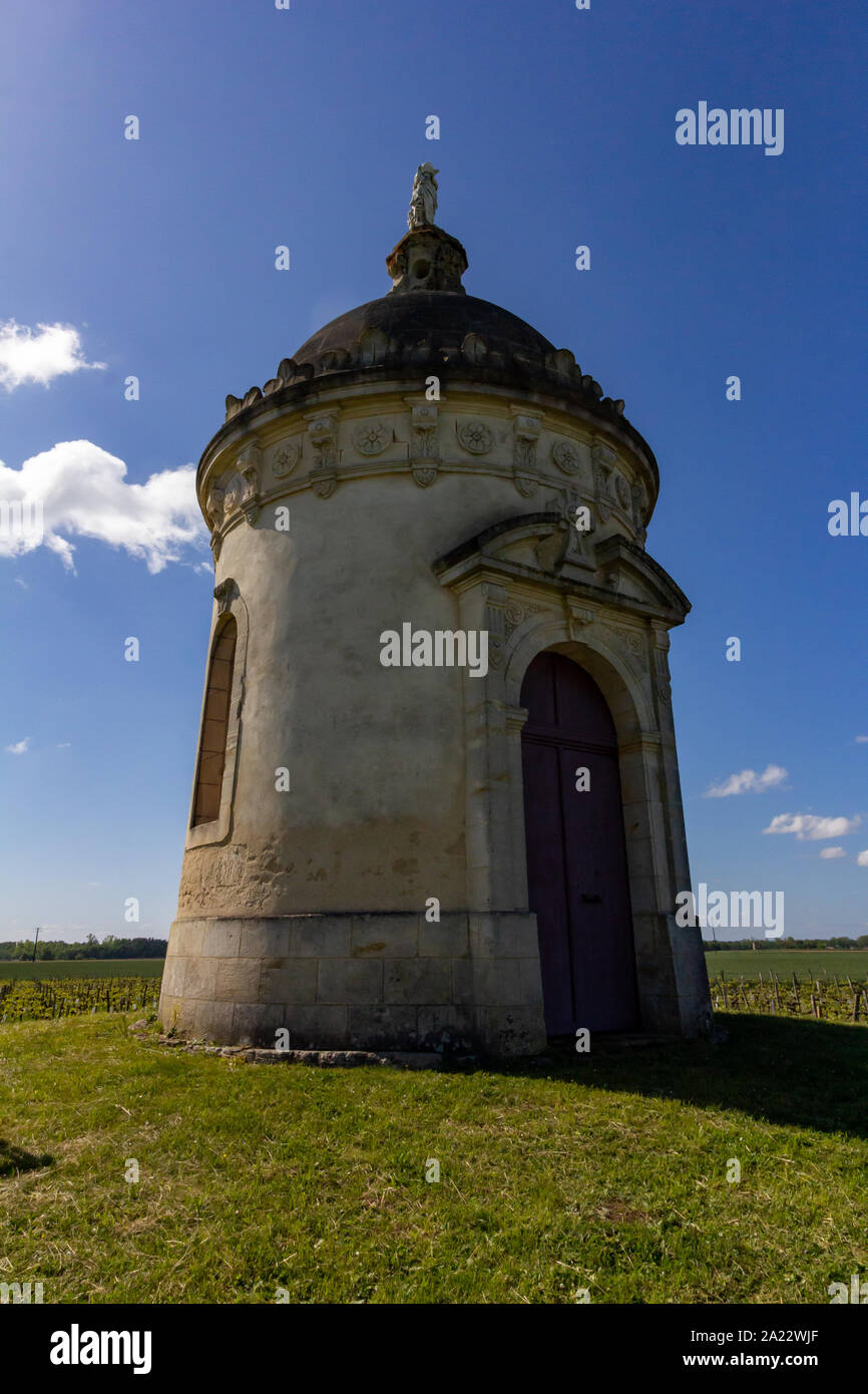 Trovati nel mezzo di un vigneto di Bordeaux, una torre rotonda cappella sorge su una piccola collina Foto Stock