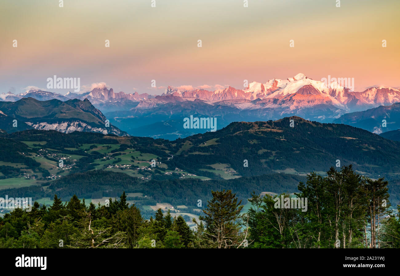 Paesaggio alpino, Mont Blanc picco di montagna, il massiccio del Monte Bianco, Savoy Prealpi gamma,Tramonto illumina le cime della montagna in arancione. Foto Stock