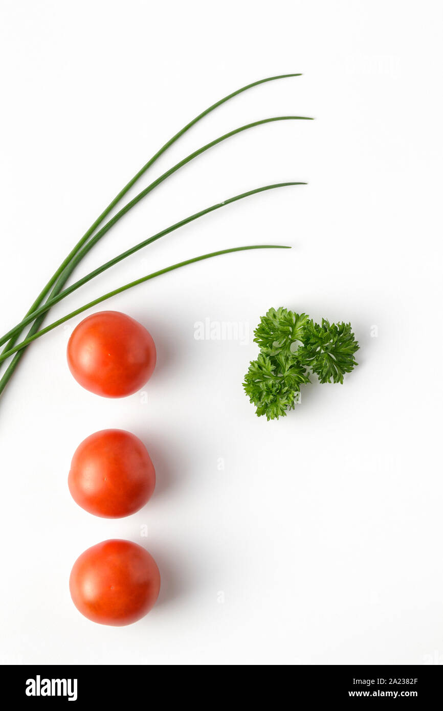 Il pomodoro fresco, erba cipollina e prezzemolo su sfondo bianco Foto Stock